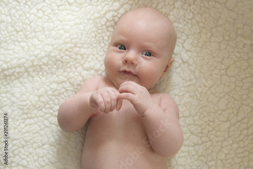 Portrait of a cute smiling newborn child against a white sheepskin