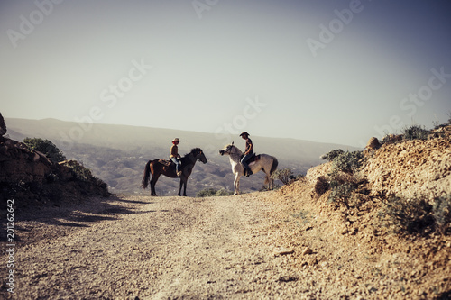 emotional image with two horses and a coulpe riding in the nature photo