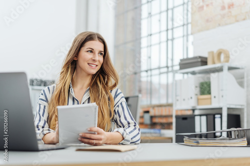 Young smiling woman holding notepad in office © contrastwerkstatt