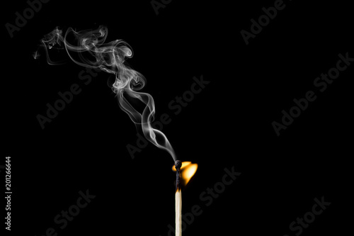 Matchstick burning with little flame and smoke on black background
