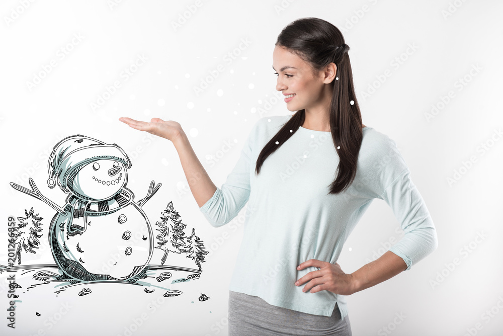 Lovely snowman. Kind cheerful young mother showing a pretty little snowman and smiling Lovely snowman. Kind cheerful young mother showing a pretty little snowman and smiling