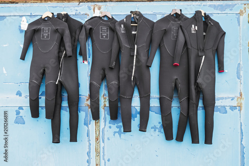 A number of wetsuits drying in summer sun on an old distressed door after use in surfing. photo