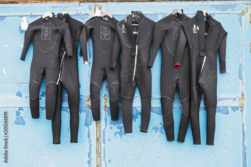 Schilderij op canvas A number of wetsuits drying in summer sun on an old distressed door after use in surfing