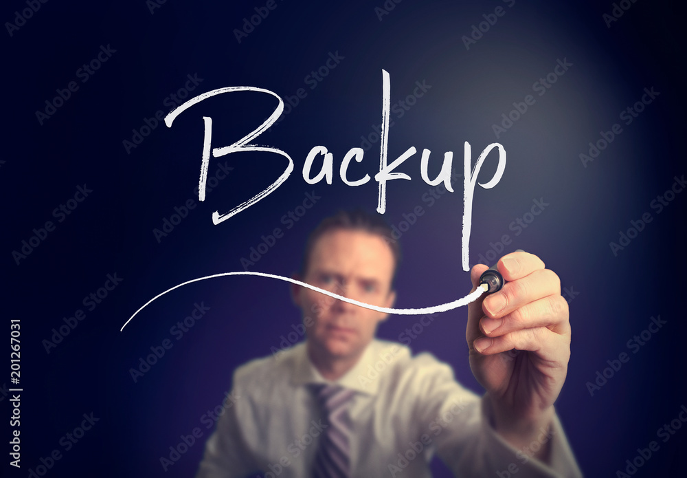 A businessman writing a Backup concept with a white pen on a clear screen. A businessman writing a Backup concept with a white pen on a clear screen.