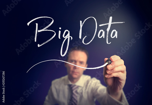 A businessman writing a Big Data concept with a white pen on a clear screen.