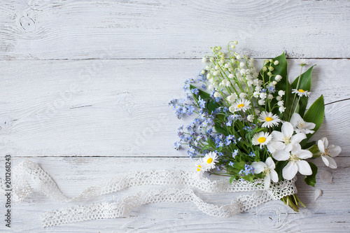 Bouquet of spring flowers lilies of the valley, forget me nots and daisies on a wooden background photo