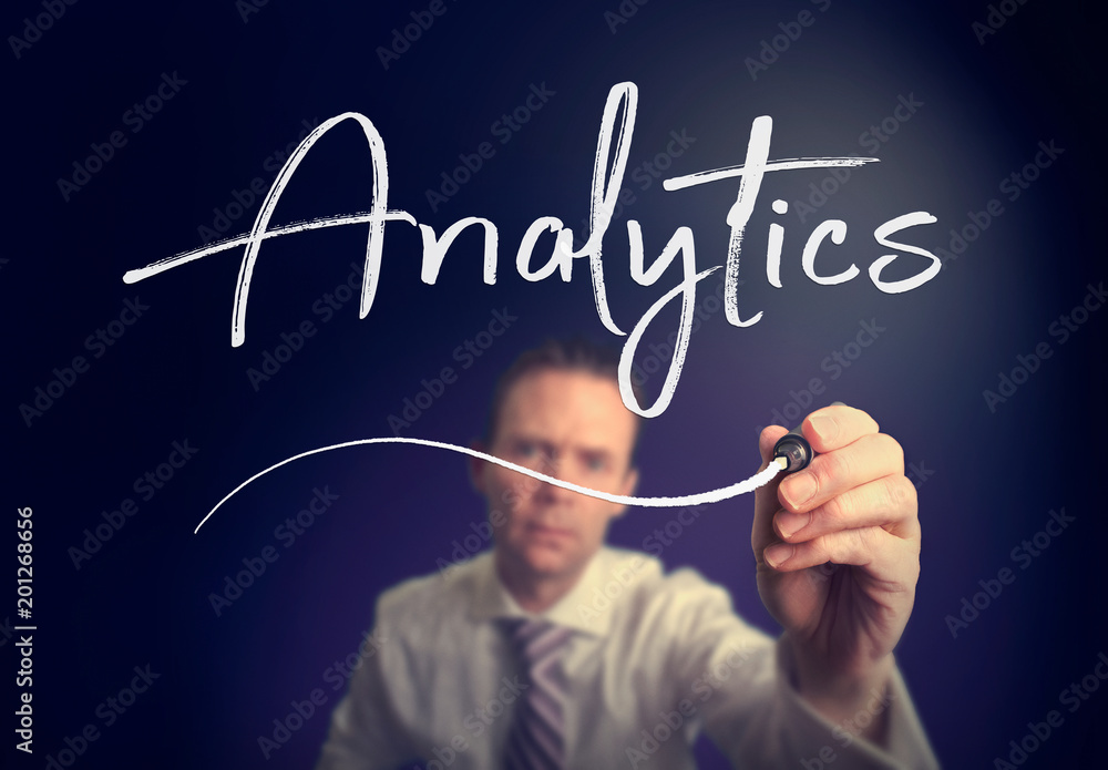A businessman writing a Analytics concept with a white pen on a clear screen. A businessman writing a Analytics concept with a white pen on a clear screen.