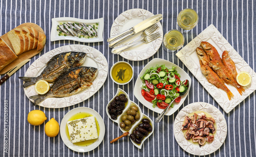 Freshly cooked seafood grilled sea bream fishes, fried red mullets, octopus in vinegar sauce, sardines in olive oil and vegetable salad, olives, feta cheese, bread, wine served for two persons.