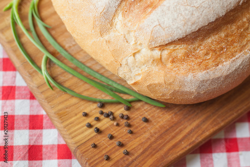 Crusty loaf at top view are on a wood table with pepper and green onion photo