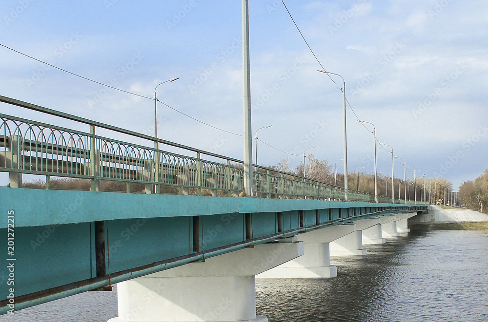 Long concrete bridge over broad river, blue sky for background