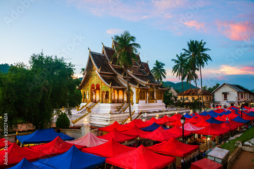 Famous night market in Luang Prabang, Laos with illuminated temple and sunset sky photo