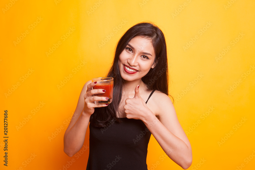 Young Asian woman thumbs up with tomato juice. Young Asian woman thumbs up with tomato juice.