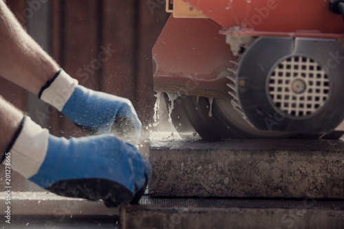 Fototapeta Naklejka Na Ścianę i Meble -  Retro image of workman using an angle grinder or circular saw to cut a concrete block