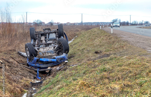 Traffic accident. A blue car overturned. The car lies in a roadside ditch.