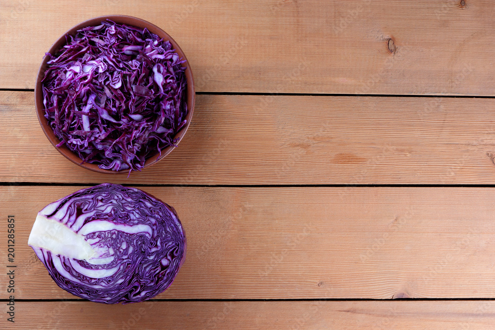 Chopped purple cabbage on a wooden background, red cabbage in a clay bowl, copy space, rustic style, vegetarian food, half fresh cabbage, minimalism, art Chopped purple cabbage on a wooden background, red cabbage in a clay bowl, copy space, rustic style, vegetarian food, half fresh cabbage, minimalism, art