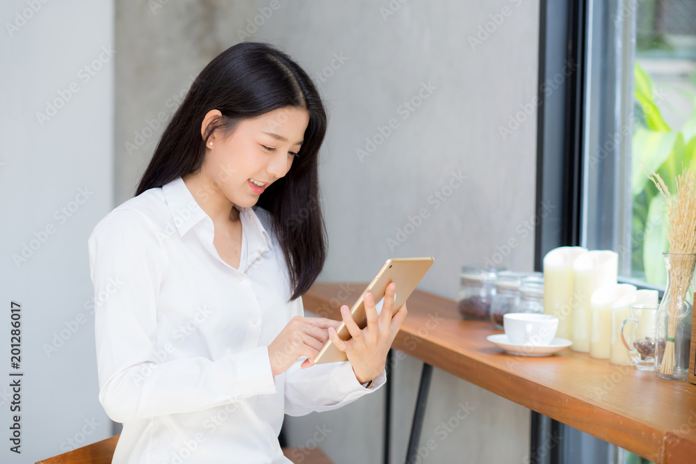 Beautiful portrait young asian woman using tablet computer in the coffee shop, businesswoman sitting looking tablet is work at cafe, communication concept. Beautiful portrait young asian woman using tablet computer in the coffee shop, businesswoman sitting looking tablet is work at cafe, communication concept.
