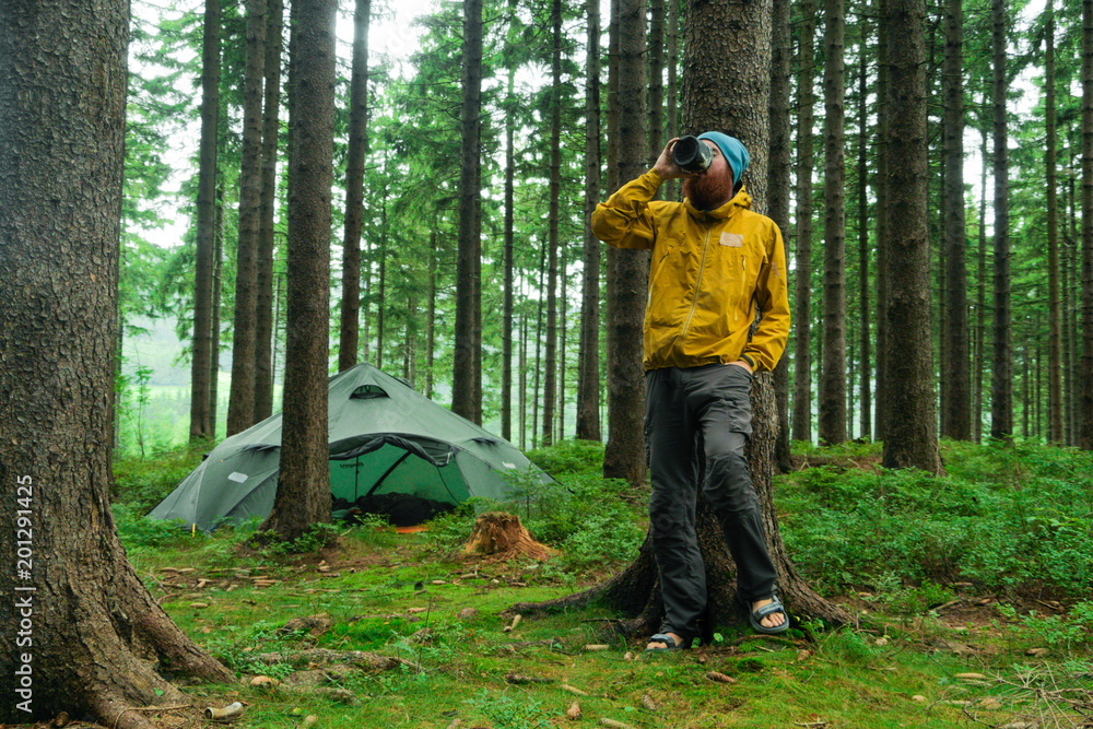 portrait of a caucasian male hiker standing in a forest holding a mug with coffee portrait of a caucasian male hiker standing in a forest holding a mug with coffee