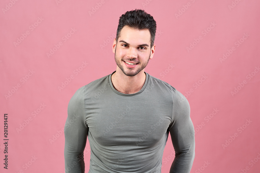 sportive young man in a gray t-shirt smiles friendly. sturdy figure, athletic tight-fitting t-shirt and a confident posture. sportive young man in a gray t-shirt smiles friendly. sturdy figure, athletic tight-fitting t-shirt and a confident posture.