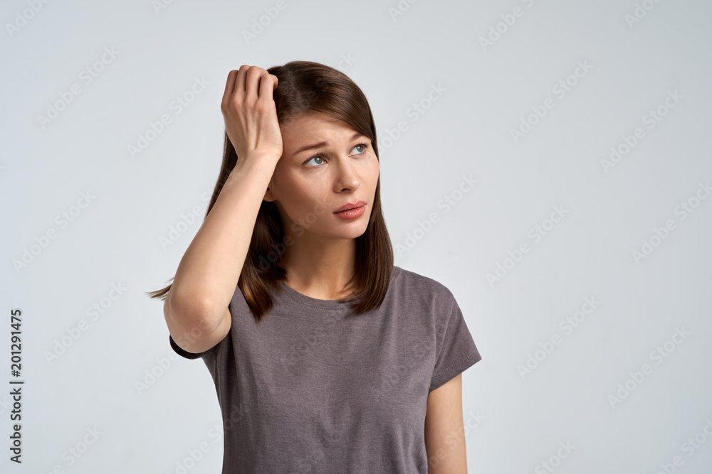 Studio portrait on isolated background of a beautiful young brunette woman with a thoughtful expression scratching her nape Studio portrait on isolated background of a beautiful young brunette woman with a thoughtful expression scratching her nape