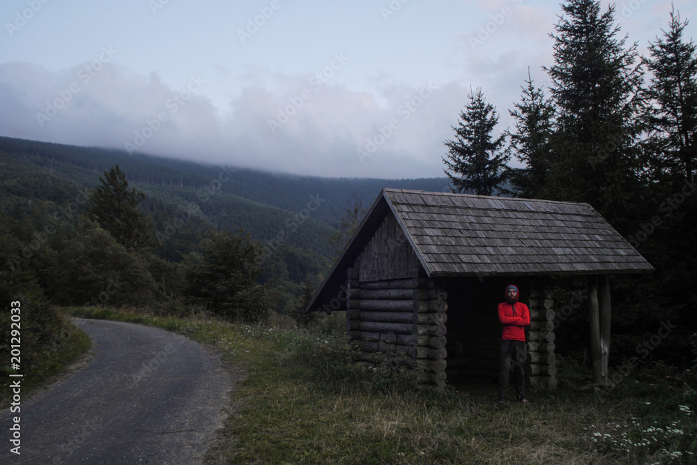 simple wooden cabin used as a hiking shelter with hiker standing inside, czech republic