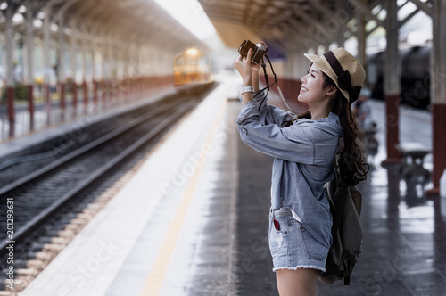 Young beautiful woman traveler with backpack holding vitage camera and taking photos photo