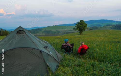 outdoors couple  man and woman  sitting in front of a tent on camping chairs