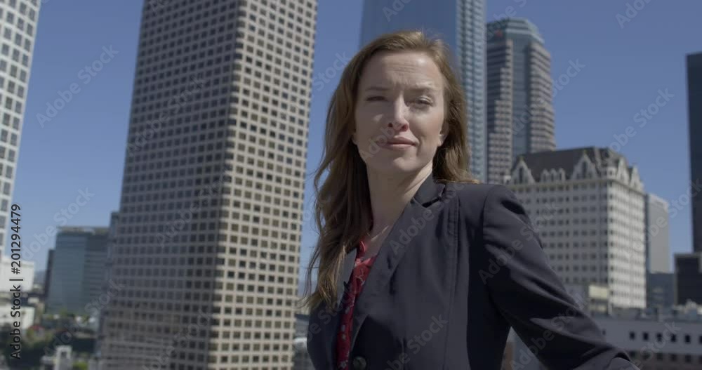 Medium close up, smartly dressed business woman with serious expression, standing in front of skyscrapers in Downtown Los Angeles. Hand-held, slow motion 4K recorded at 60fps Medium close up, smartly dressed business woman with serious expression, standing in front of skyscrapers in Downtown Los Angeles. Hand-held, slow motion 4K recorded at 60fps