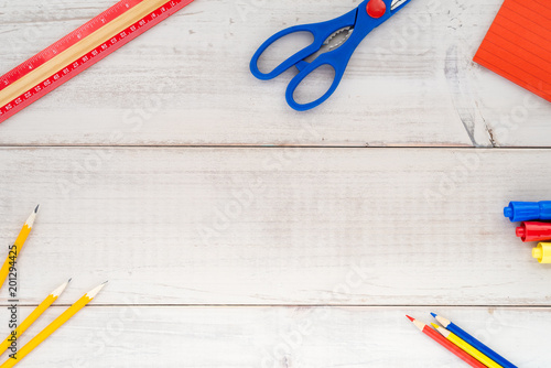Assorted school supplies in primary colors on a wood plank table
