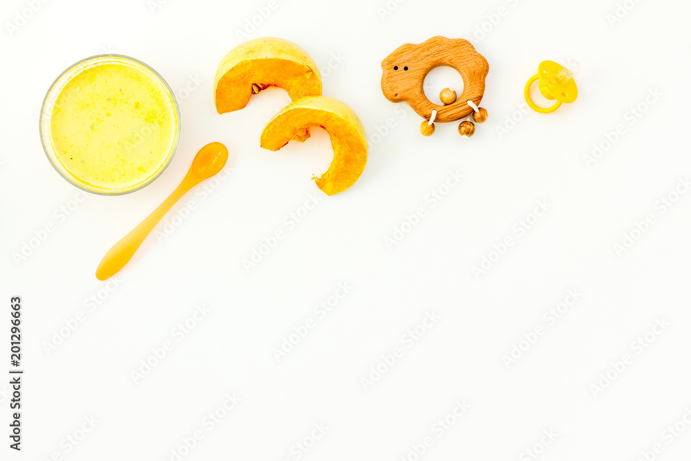 Healthy food for little baby. Puree with pumpkin near pacifier and toys on white background top view copy space