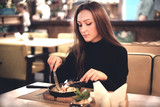 Young elegant brunette woman enjoy eating meal in the restaurant