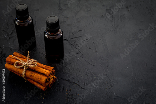 Cinnamon oil for cooking, aromatheraphy, skin care. Bottles near cinnamon sticks on black background space for text