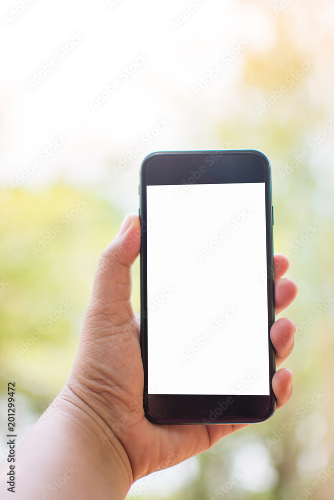 hand holding smart phone on nature background. Subject is blurred. hand holding smart phone on nature background. Subject is blurred.