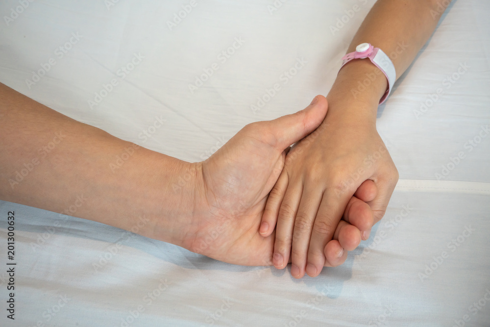 Fototapeta premium Parent holds the hand of a sick child in a hospital.