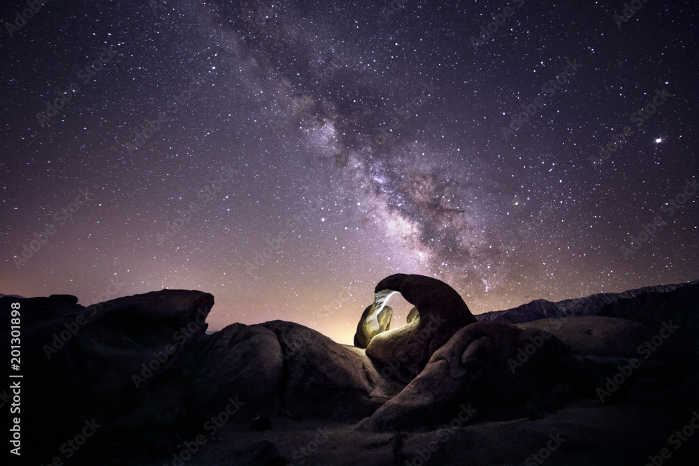 Lanscape view of the desert with stars and milky way galaxy over the night sky.  The image depicts astrophotography and nature.  