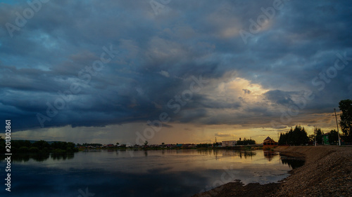 Dramatic rain clouds above the river on the sunset