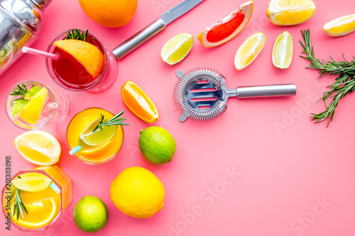 Bartender workplace for make fruit cocktail with alcohol. Shaker, strainer and other bar tools near citrus fruits and glass with cocktail on pink background top view copy space
