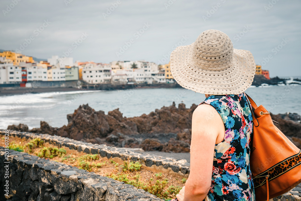 Back view of female tourist with rucksack admires view of Santa Cruz de Tenerife