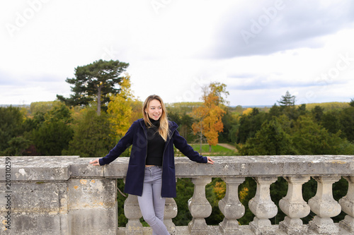 Female person standing near concrete railing with green trees background. Concept of architectural elements and visiting Europe. photo