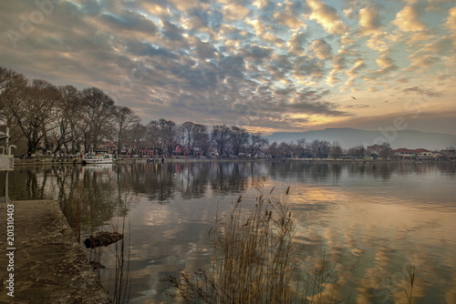 Scenery of Ioannina city lit up by yellow sunlight  colors  and glowing sky with reflections on the smooth lake water photo