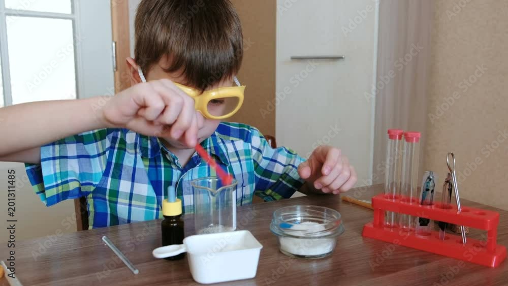 Experiments on chemistry at home. Boy mixes the substances and the blue liquid in the beaker. Experiments on chemistry at home. Boy mixes the substances and the blue liquid in the beaker.