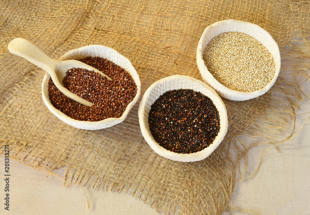 Red, white and black quinoa on a burlap cloth on a canvas background Red, white and black quinoa on a burlap cloth on a canvas background