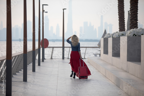 Photography Beautiful woman in a red dress comes with a suitcase.