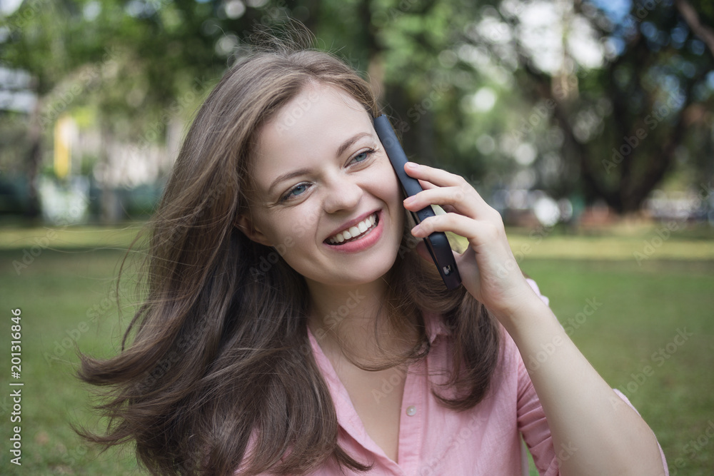 Young caucasian woman talking on the phone, looks happy. Outdoor picture Young caucasian woman talking on the phone, looks happy. Outdoor picture
