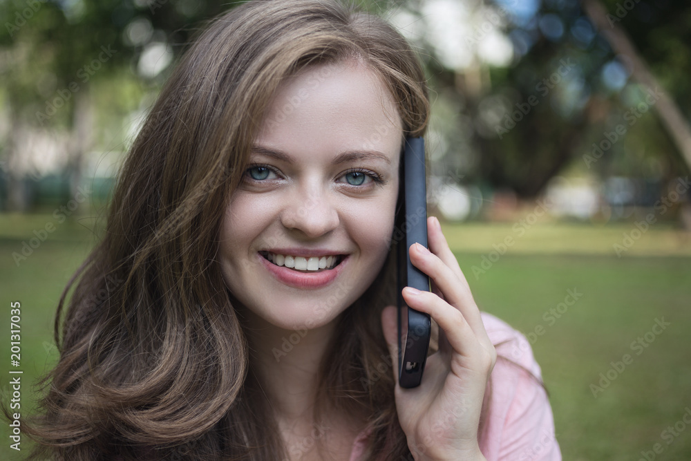 Young caucasian woman talking on the phone. Outdoor in the park 