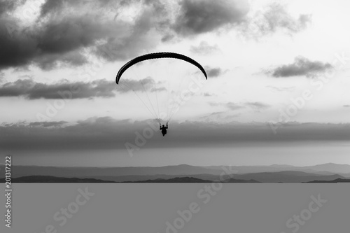 Beautiful shot of a paraglider silhouette flying over Monte Cucco (Umbria, Italy), with sunset on the background