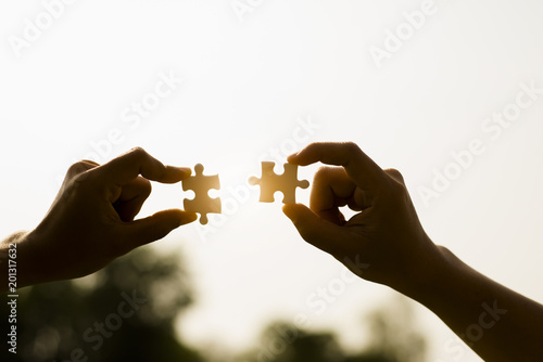 Closeup hands of woman and man connecting jigsaw puzzle photo