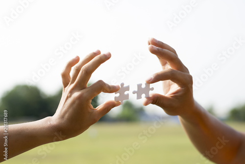 Closeup hands of woman and man connecting jigsaw puzzle