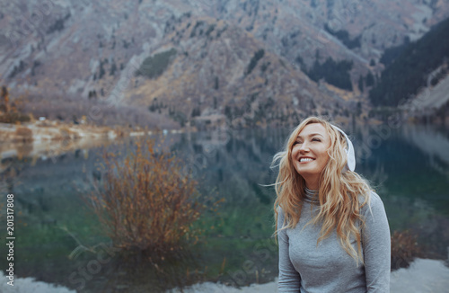 Woman wearing wireless headphones at the mountain lake © Arman Zhenikeyev