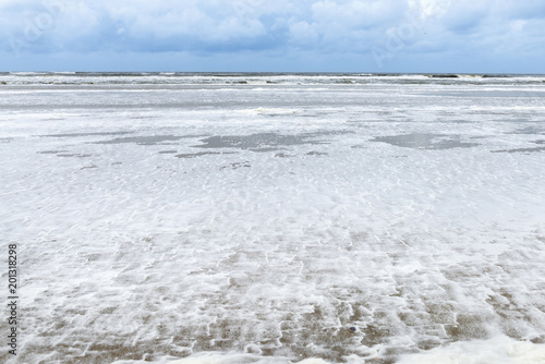 Deutschland, Niedersachsen, Ostfriesland, Juist, schaumiges Meerwasser am Strand.