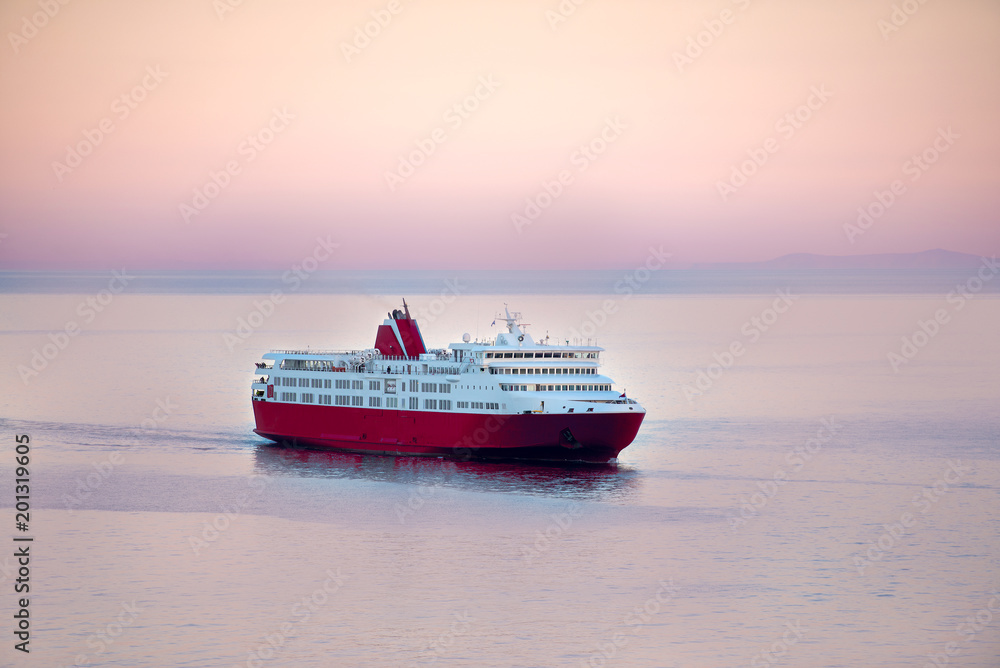 Sunset and a blue white ferry boat in greek islands